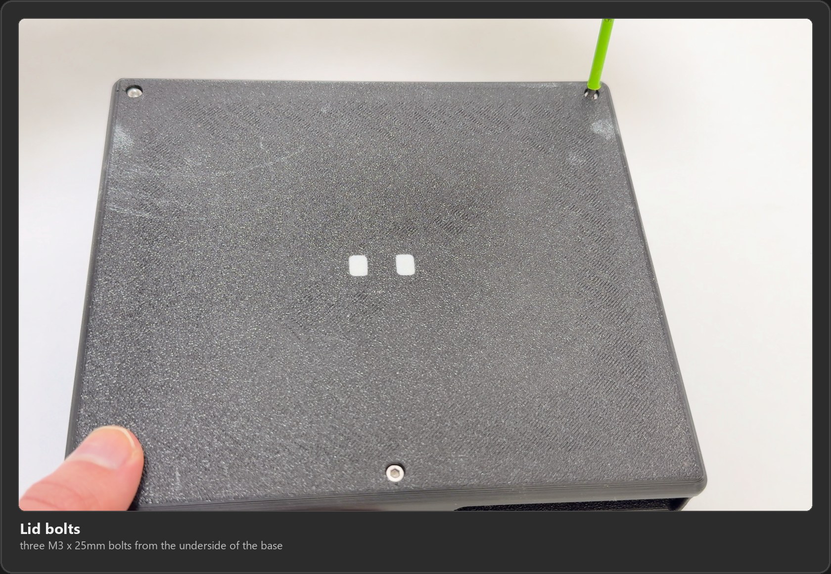 The underside of the base with the three M3 x 25mm bolts that hold the lid on, one being tightened with a hex driver