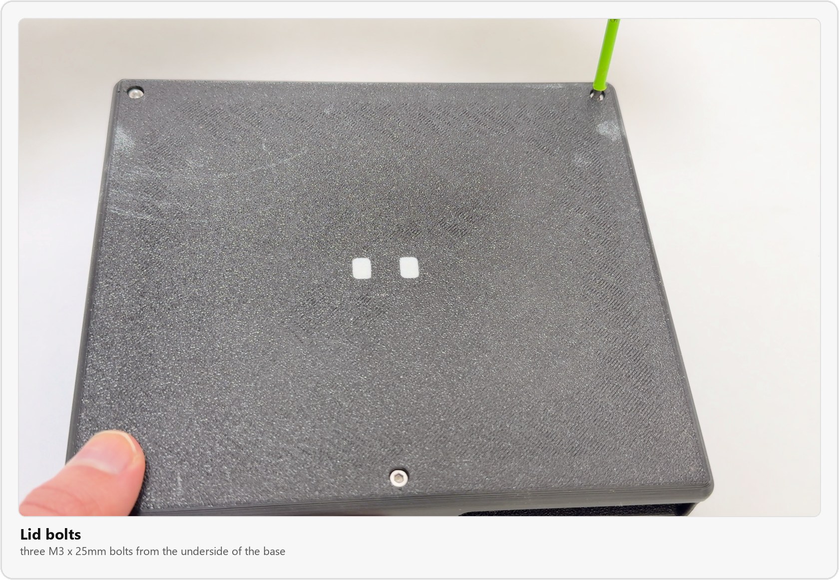 The underside of the base with the three M3 x 25mm bolts that hold the lid on, one being tightened with a hex driver